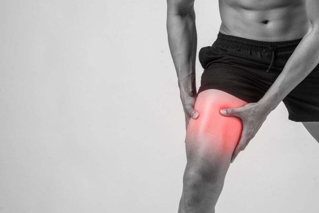 young sport man with strong athletic legs holding knee with his hands in pain after suffering ligament injury isolated on white